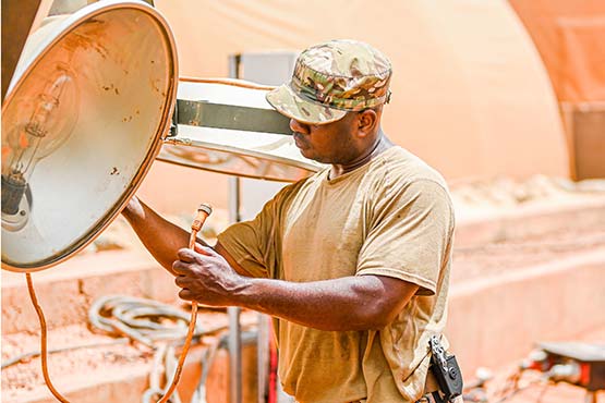 Airman connecting lighting equipment in the dessert