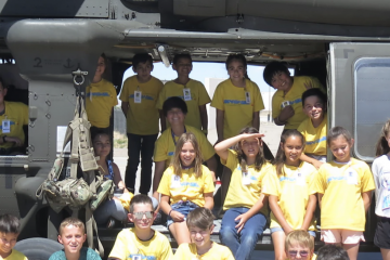Members of the New Mexico Army National Guard, from left, Capt. Dustin Offret, Chief Warrant Officer 3 Anita Guderjohn, Sgt. Benjamin Vasquez, and students stand in front of an Army UH-60 Black Hawk helicopter during the Air Force Research Laboratory's DOD STARBASE STEM Camp at Kirtland Air Force Base, New Mexico, June 14, 2022.